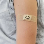 Close de um curativo inteligente transparente aplicado na pele, mostrando sensores eletrônicos e circuitos flexíveis integrados.