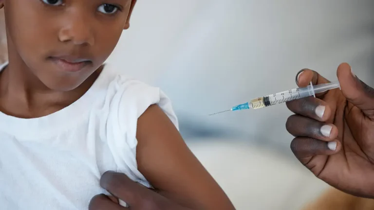 Criança recebendo a primeira dose da vacina contra a malária em um posto de saúde na África, um marco histórico.